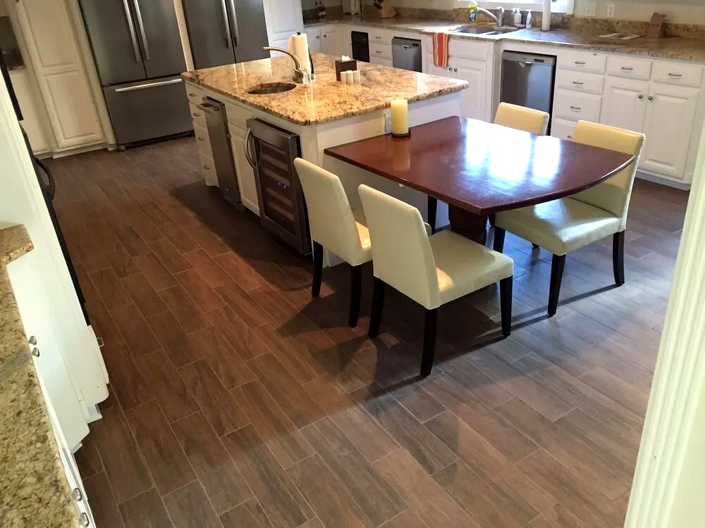 Kitchen with plank-style flooring running beneath an island and dining table