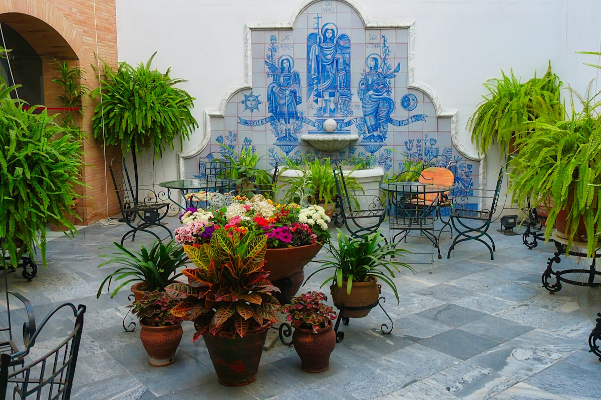 Courtyard with a blue-and-white tiled wall fountain and potted plants