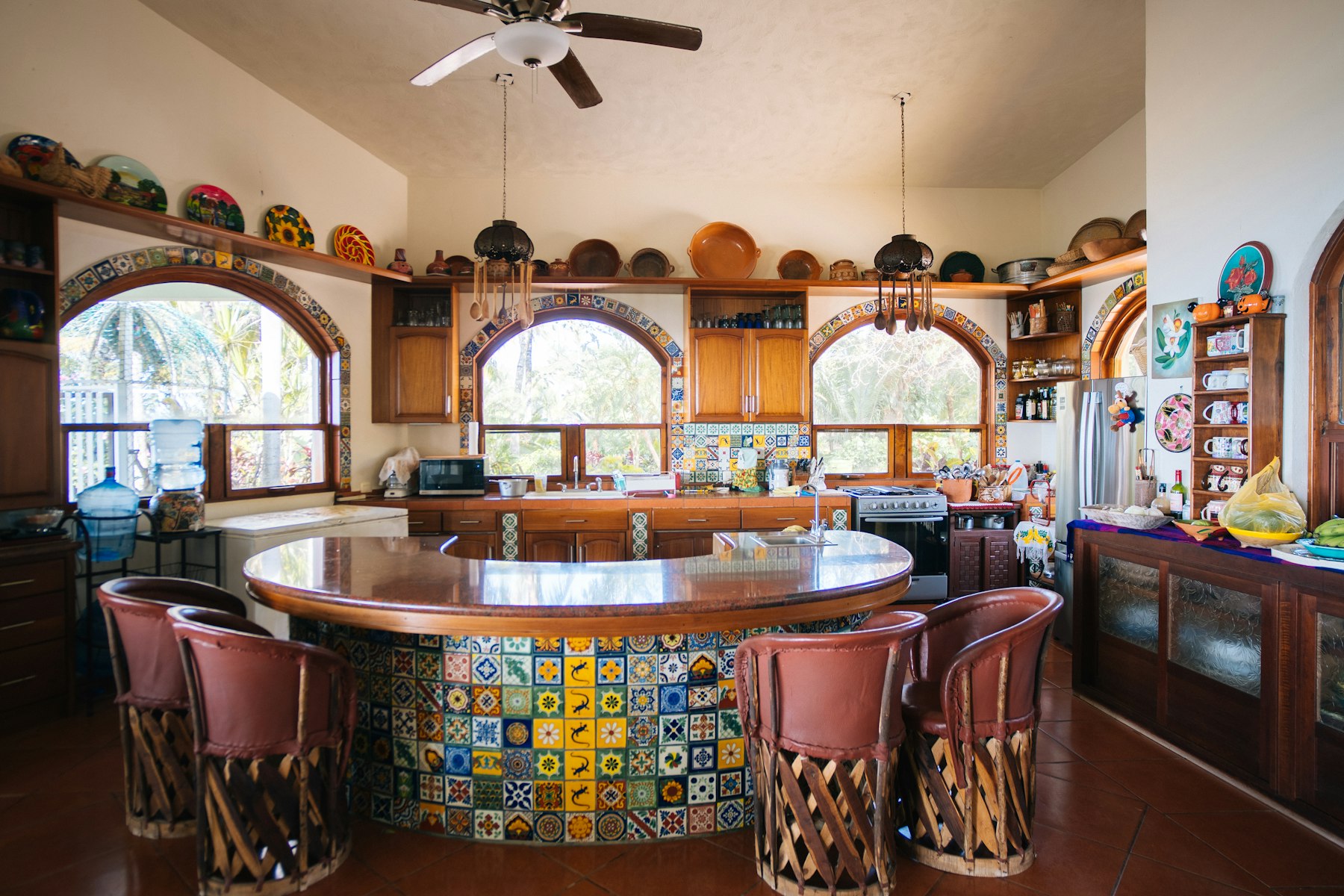 Kitchen with a hand-painted tile island, wood cabinets and arched windows